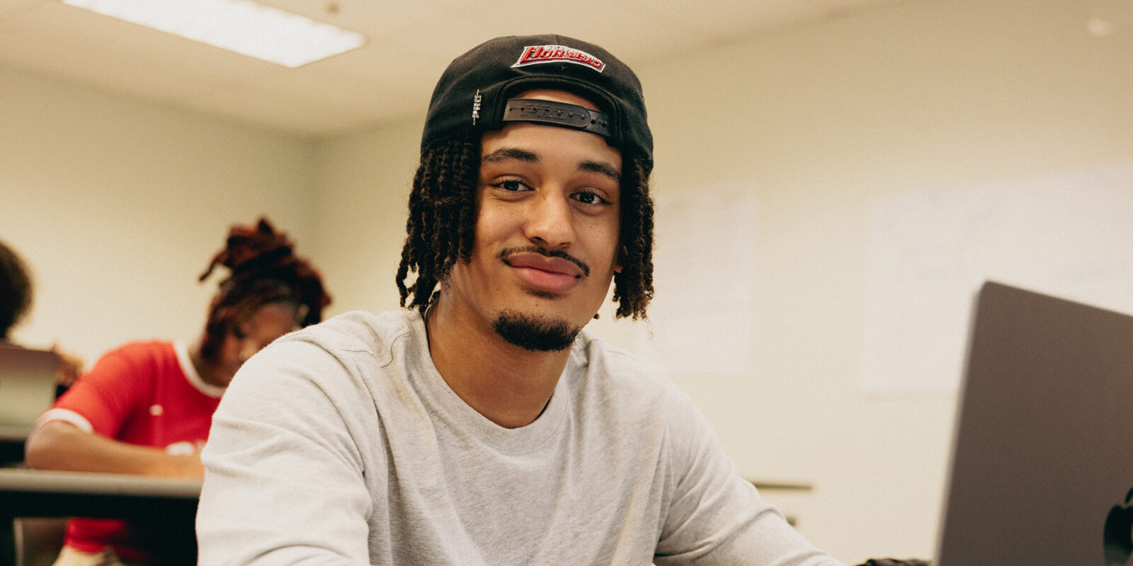 Delaware State student in class on laptop smiles at camera